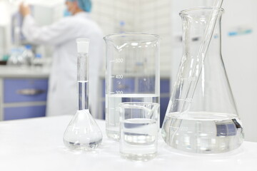 Blur male scientist working in a Chemistry Science laboratory  with flask, beaker and glassware containing clear liquid chemical.