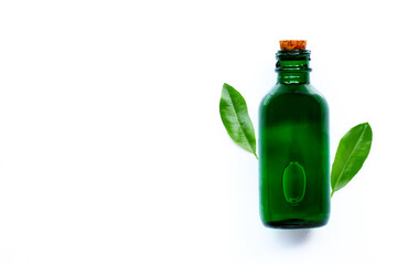 Essential oil bottle with green leaves on white background.