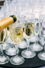 the waiter pours champagne in glasses on the street - wedding catering - look from below