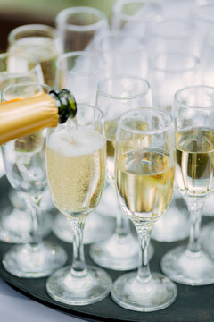the waiter pours champagne in glasses on the street - wedding catering - look from below
