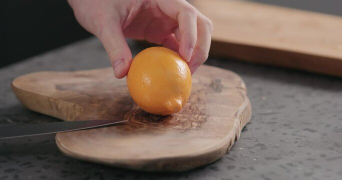 Slow motion man cut fresh orange lemon on olive board