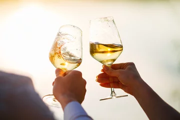Gardinen glasses with white wine splash in the hands © NEZNAEV