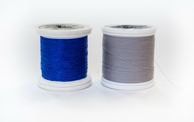 Two coils of blue and gray threads on white background
