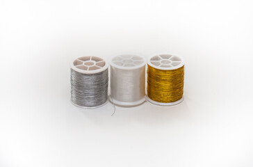 Three coils of gold and silver and gray threads on a white background