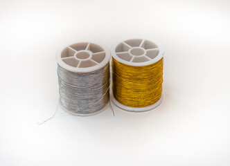 Two coils of gold and silver threads on a white background