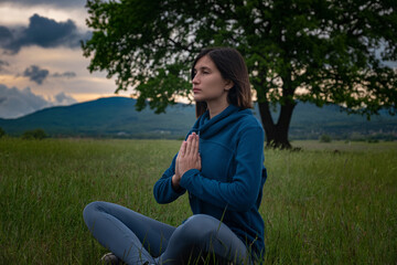 A young woman doing yoga in the field.