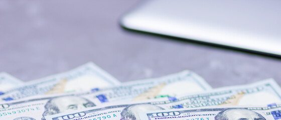 One hundred dollars. American currency. Tablet and hundred dollar bills on a gray background. Financial investment. Copy space