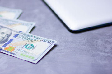 One hundred dollars. American currency. Tablet and hundred dollar bills on a gray background. Financial investment. Copy space