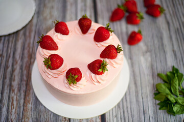 Creamy cake with strawberries on a wooden background.