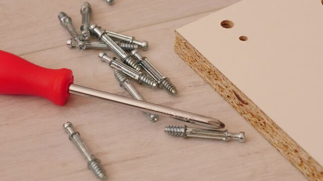 Assembling furniture at home. Many mounting screws with screwdriver and board on floor.  Do it yourself furniture assembly