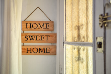 Home sweet home text on a wooden nameplate at the entrance to house. Home decoration concept.