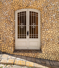 Entrance door to an old house decorated with pebbles. Mediterranean architecture and stone streets.