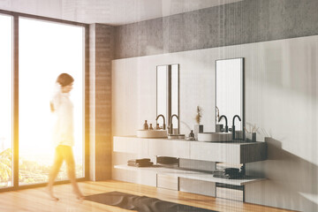 Woman walking in white bathroom corner with sink