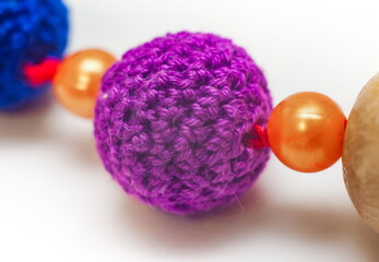 Slingobusy. Wooden ball tied with purple yarn close-up on white background