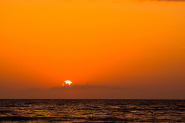 Fototapeta premium Amazing sea sunset on the pebble beach, the sun, waves, clouds