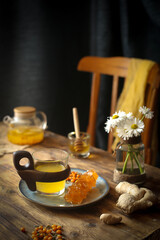 On the table is a cup of coffee, a kettle, flowers and a chair.
