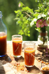 Near the window on a wooden table is a bottle with kvass and two glasses
