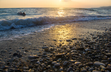 Amazing sea sunset on the pebble beach, the sun, waves, clouds