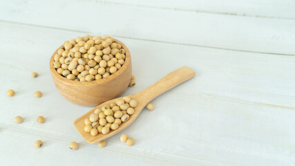 Soybeans in a wooden blow and spoon on white wood texture background with copy space.