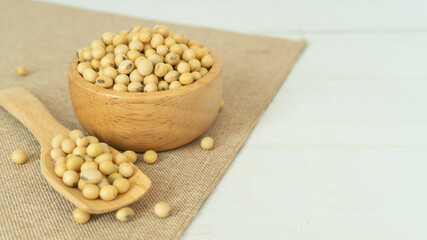 Soybeans in a wooden blow and spoon on white wood texture background with copy space.
