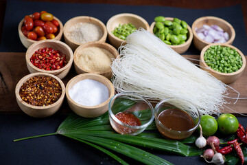 Raw rice flour in a wooden bowl with spices On a dark wood with natural light, focusing on the top of the noodles