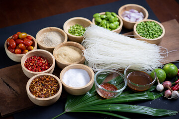 Raw rice flour in a wooden bowl with spices On a dark wood with natural light, focusing on the top of the noodles