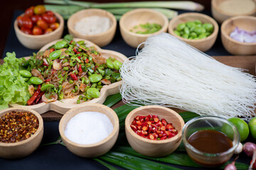 Raw rice flour in a wooden bowl with spices On a dark wood with natural light, focusing on the top of the noodles