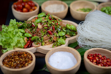 Raw rice flour in a wooden bowl with spices On a dark wood with natural light, focusing on the top of the noodles