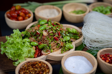 Raw rice flour in a wooden bowl with spices On a dark wood with natural light, focusing on the top of the noodles