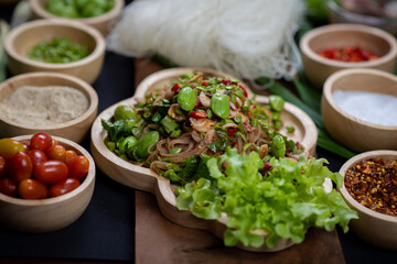 Raw rice flour in a wooden bowl with spices On a dark wood with natural light, focusing on the top of the noodles