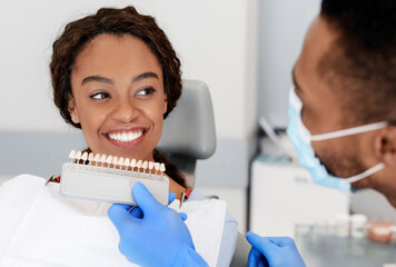 Dentist applying tooth scale samples set to smiling patient