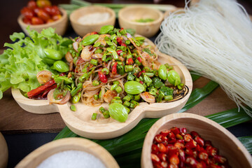 Raw rice flour in a wooden bowl with spices On a dark wood with natural light, focusing on the top of the noodles