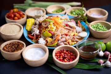 Raw rice flour in a wooden bowl with spices On a dark wood with natural light, focusing on the top of the noodles