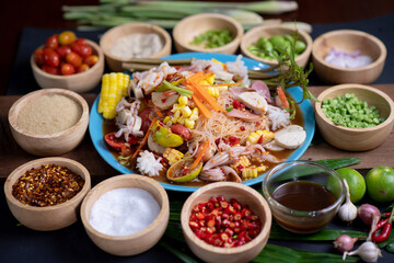 Raw rice flour in a wooden bowl with spices On a dark wood with natural light, focusing on the top of the noodles