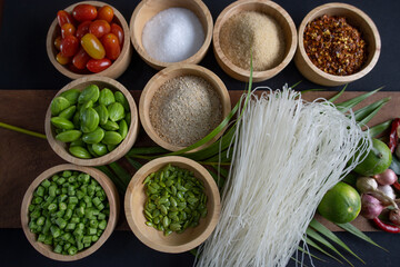 Raw rice flour in a wooden bowl with spices On a dark wood with natural light, focusing on the top of the noodles
