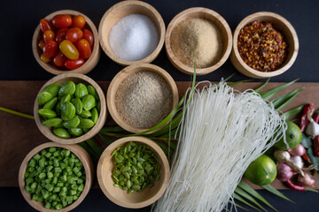 Raw rice flour in a wooden bowl with spices On a dark wood with natural light, focusing on the top of the noodles