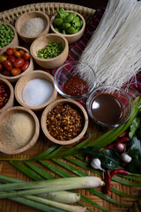 Raw rice flour in a wooden bowl with spices On a dark wood with natural light, focusing on the top of the noodles