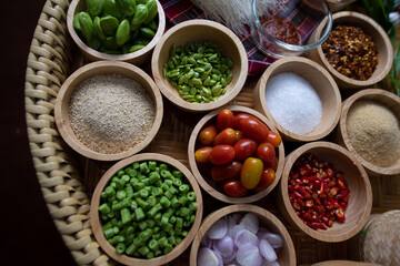 Raw rice flour in a wooden bowl with spices On a dark wood with natural light, focusing on the top of the noodles