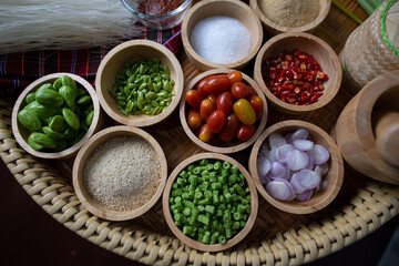 Raw rice flour in a wooden bowl with spices On a dark wood with natural light, focusing on the top of the noodles