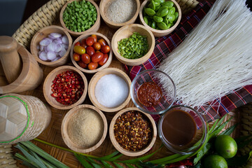 Raw rice flour in a wooden bowl with spices On a dark wood with natural light, focusing on the top of the noodles