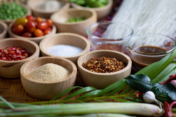 Raw rice flour in a wooden bowl with spices On a dark wood with natural light, focusing on the top of the noodles