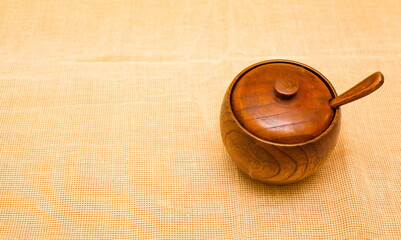 Wooden salt shaker with a spoon on a beige napkin