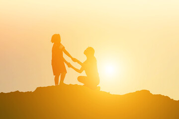 Mother encouraged her daughter out of the shadows at sunset.