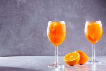 Aperol spritz cocktail on a gray background. Two glasses of aperol spritz with orange slised. Summer italian cocktail in glass. Copy space