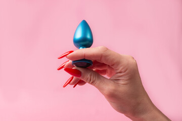 Dildo in hand on a pink background, sex toy