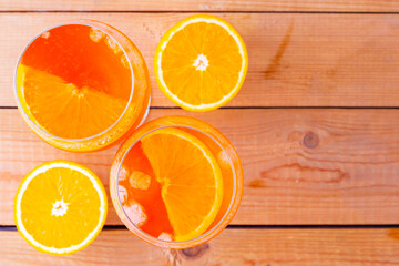 Aperol spritz cocktail on a wooden boards. Two glasses of aperol spritz with orange slised. Summer cocktail in glass. Top view. Copy space