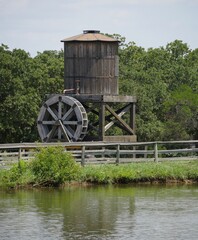 Old wooden waterwheel with wooden tank by a pond side © GemStocks