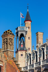Obraz premium Stepped gable, tower and tall brick chimney on the roofs of houses in Bruges