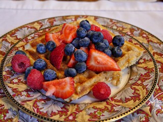 Breakfast of waffles with blueberries and sliced strawberries on top