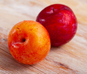 Naklejka na ściany i meble Tasty ripe red plum on a wooden surface